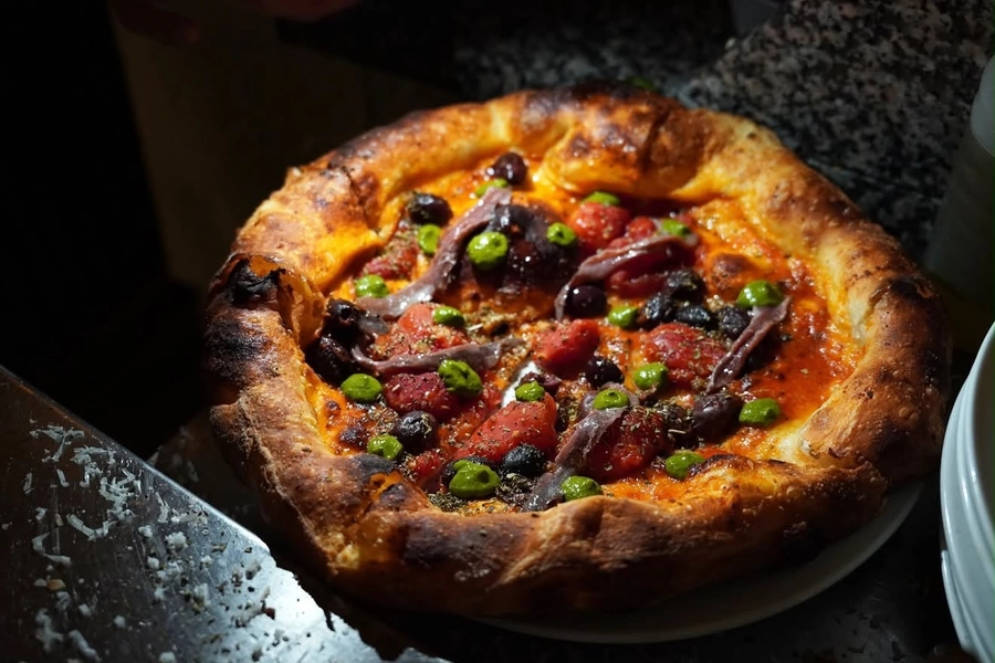 Anchovy and olive pizza with herb sauce and tomato, The Food Hub pizza catering